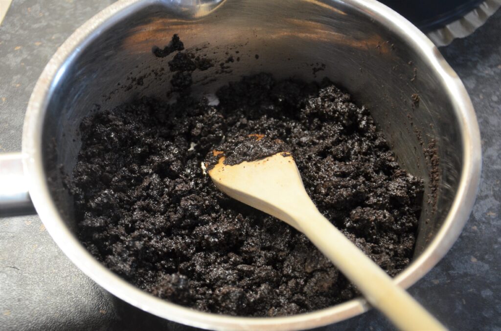 Mixing oreo crumbles with melted butter in a small sauce pan