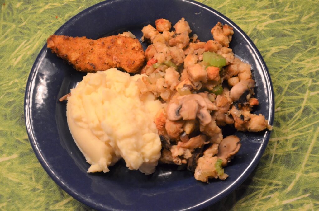 Stuffing with mashed potatoes and chicken, served on a blue plate seen from above