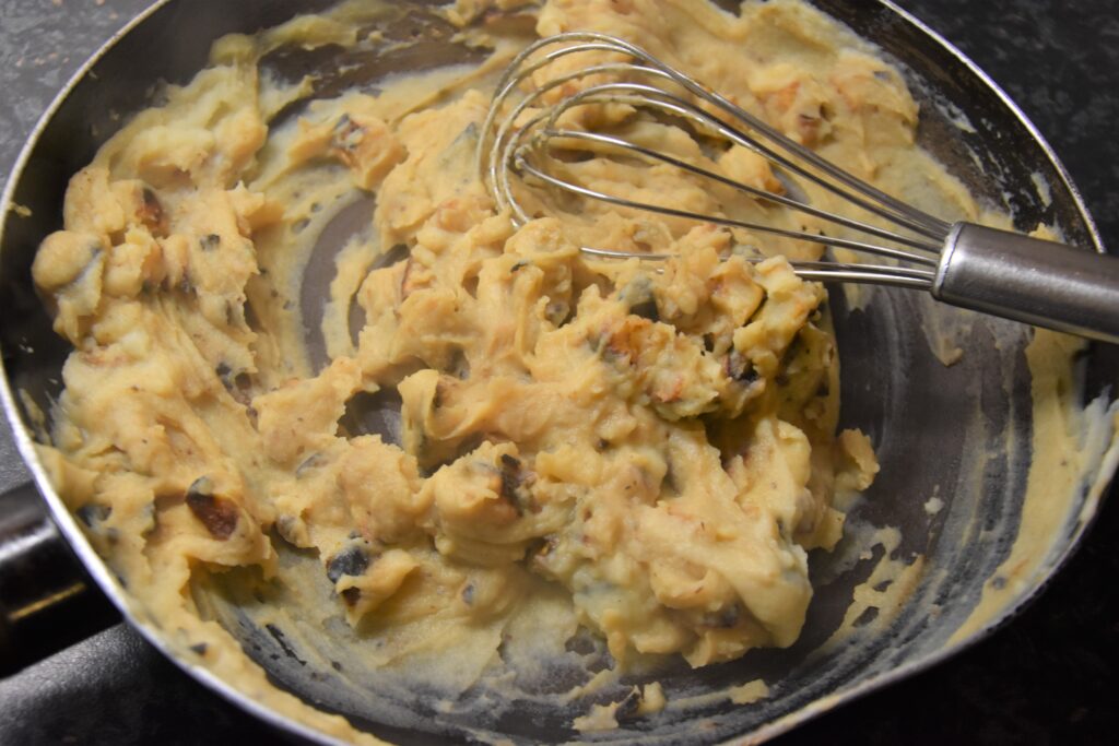 Mashed celeriac in a frying pan with a whisk