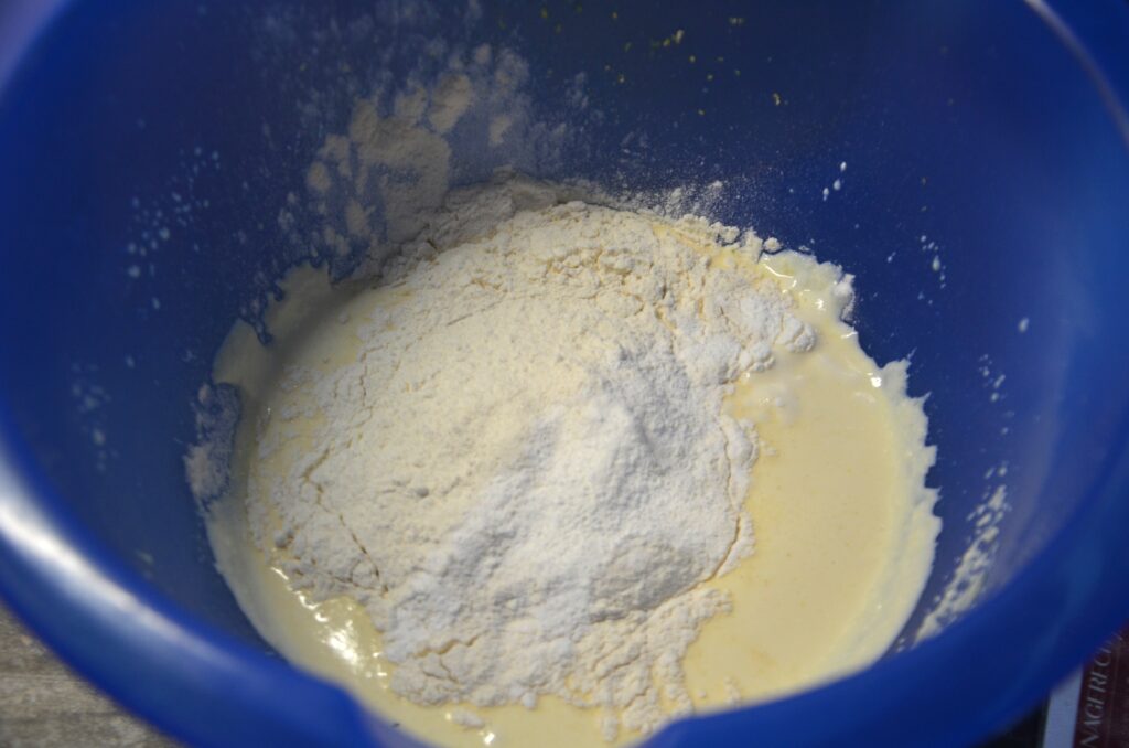Flour and baking powder added to the batter, in a blue bowl