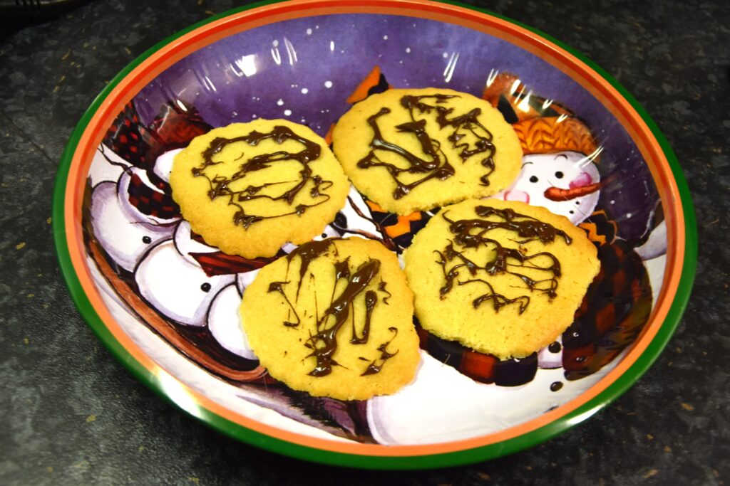 Chocolate sprinkled ginger cookies, 4 of them on a Christmas decorated serving plate