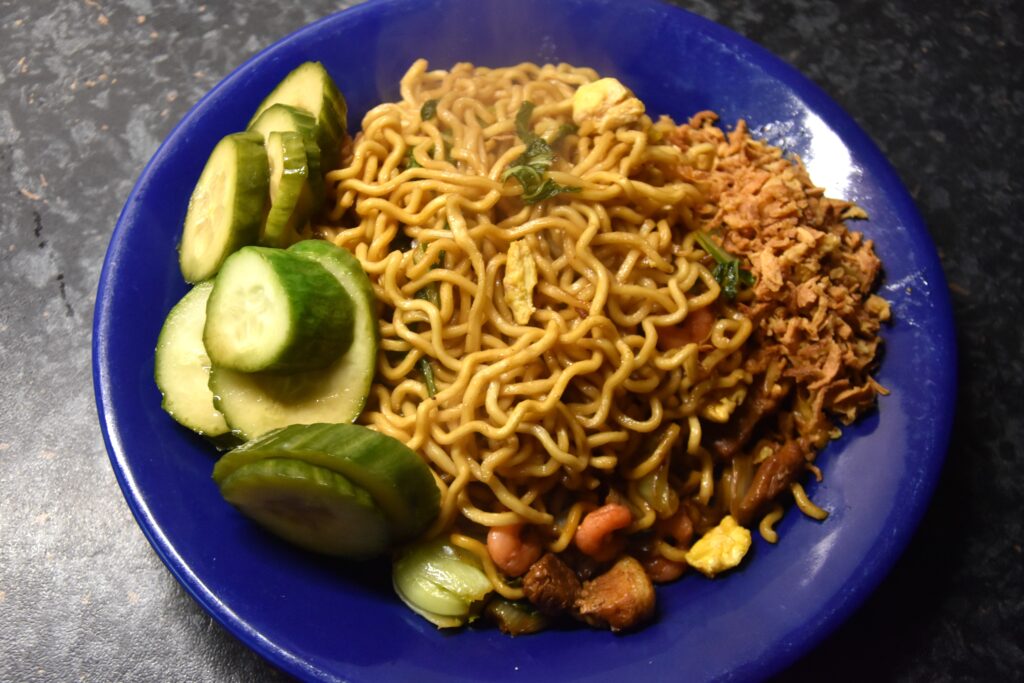 Fried noodles with pickled cucumbers, served on a blue plate