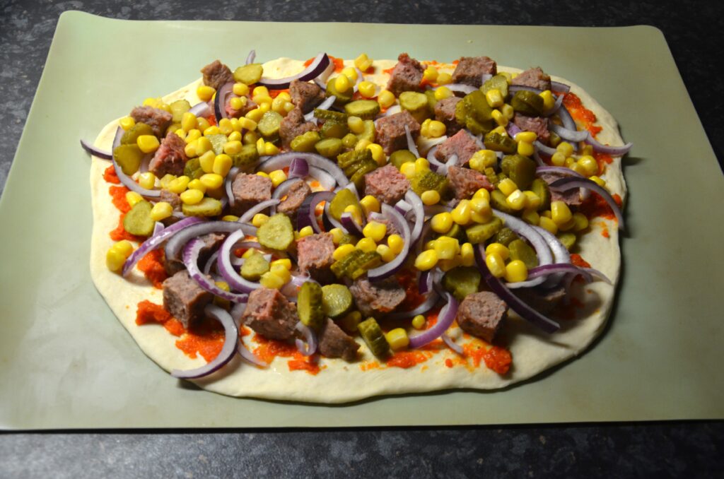 Layer of corn on the pizza, placed on a baking tray