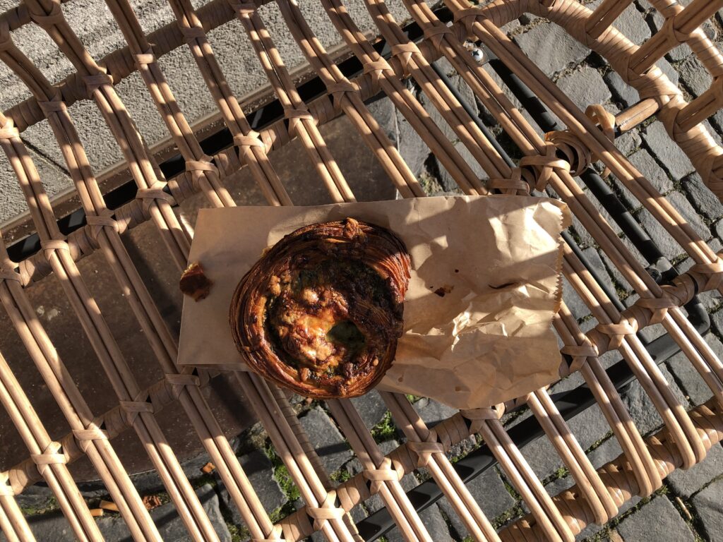 Cheese bun, seen from above on a paper bag on a bench with shadows and sun over it