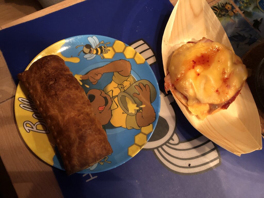 Saucijzenbroodje and a pizza bun, the saucijzenbroodje is served on a colorful plate and the pizza bun in a bamboo tray